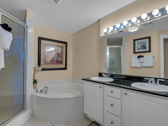 en-suite bathroom with large soaking tub, shower, double vanity, and toilet room