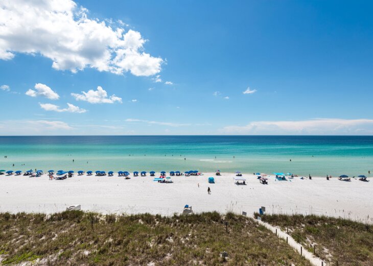 The property is located near a stunning beach featuring powdery white sand, turquoise waters, and colorful umbrellas dotting the shore—a perfect backdrop for your Gulf Coast getaway.