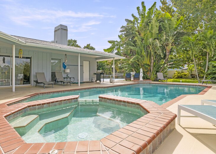 Your private oasis awaits with a sparkling pool and soothing spa, surrounded by lush tropical palms. Relax on loungers under covered patio space, fire up the grill, and soak in the sunny serenity of your backyard retreat.