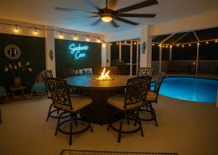 Lanai with fire table, grill, and screened pool under string lights
