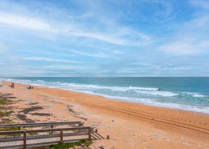 Steps to the coral colored sand and ocean. Lifeguard stand is only a few yards away.