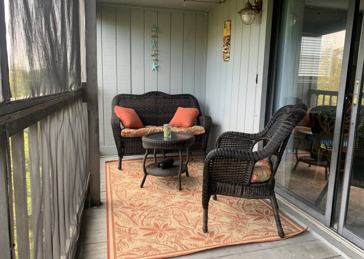 Private screened porch with cushioned wicker seating