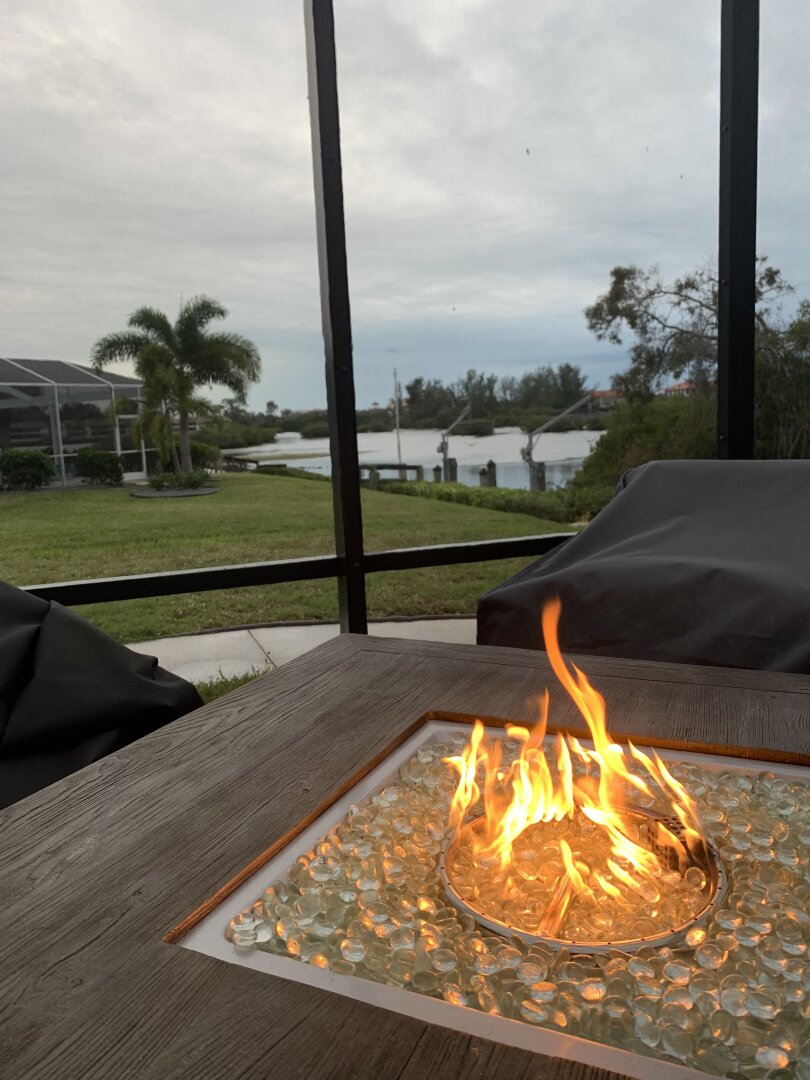 Screened lanai with gas fire table and 4 chairs with water voew