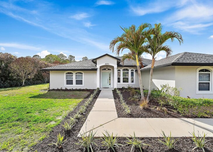 Front of the home: single-story with a palm-lined entry walk