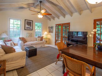 Bright living room with cathedral ceilings, smart TV, two couches, and dining