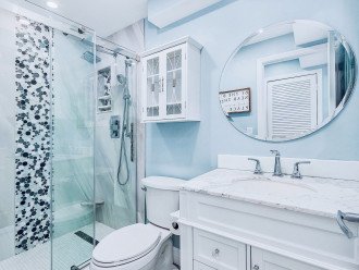 Stylish bright bathroom w/walk-in tile shower and two marble vanities.