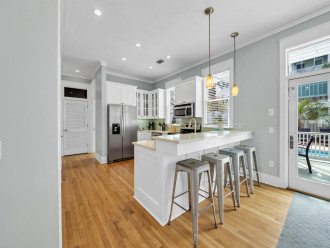 This Large White Kitchen Features Stainless Steel Appliances and Breakfast Bar