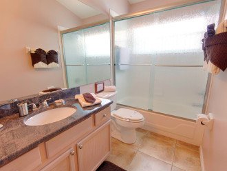 Attached bathroom with tub and overhead shower and granite vanity unit