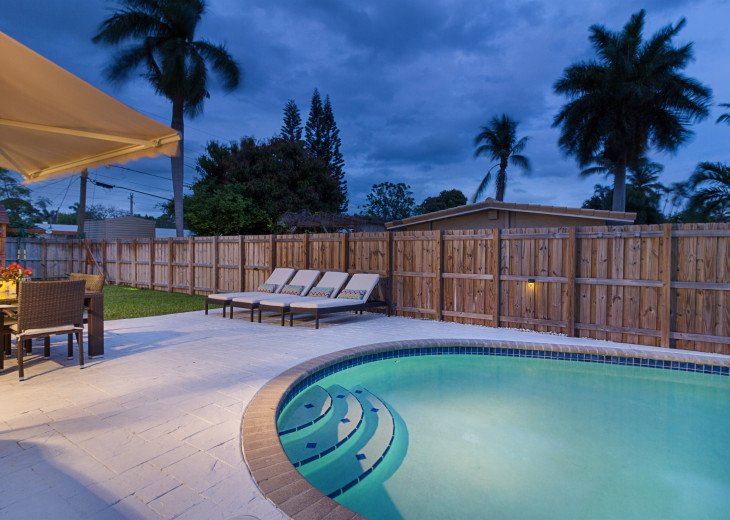 Backyard at Night with a Well Lit Pool With Pool Side Shower.