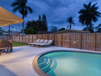 Backyard at Night with a Well Lit Pool With Pool Side Shower.