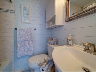 Beautiful tiled bathtub/shower and shiplapped walls.