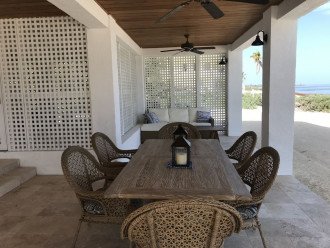 Covered porch with table, lounge area and fans.