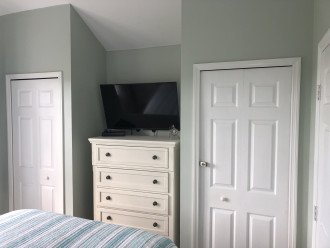 Master Bedroom closet to left and chest of drawers, large smart TV