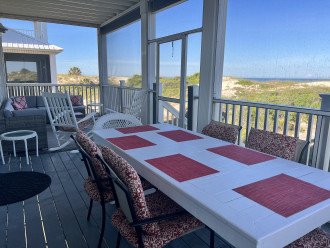 Large wood porch table and chairs on screen porch with Gulf view