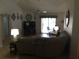 Large high ceiling living room with a 65" TV and a ceiling fan.