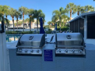 New gas grills off the pool entrance with another grill at other side on a patio
