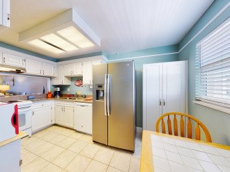 Freshly painted fully equipped kitchen with table and two chairs plus pantry.