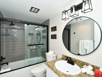 2nd bathroom with granite counters, tiled floors and glass tile shower surround