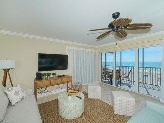 Large living room with floor-to-ceiling sliders opening to screened in Lanai - spectacular views of world famous Crescent Beach and the Gulf of Mexico. Large flat panel HDTV